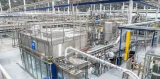 Siemens To Automate New Manufacturing Plant of DrinkPAK Industrial bottling/processing plant with stainless steel equipment, tanks, and overhead conveyors in a clean factory setting.